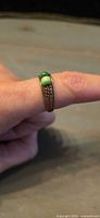 Ring on finger showing green glass bead and split shank