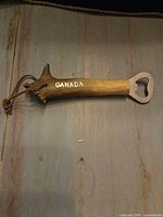 Bottle opener front showing Canada text, faux antler handle, leather loop