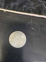 Obverse of 1976 Montreal Olympics commemorative coin showing emblem and inscription, visible wear