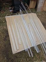 Assorted clear acrylic flat bar strips laid on plywood outdoors
