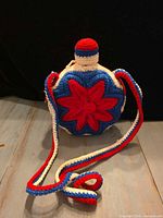 Full view of crocheted glass bottle with long strap