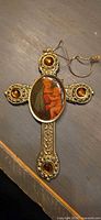 Front view of ornate gold-tone wall cross showing amber cabochons and Madonna & Child center