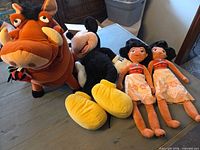 Group shot of all four plush toys: Pumbaa, Mickey Mouse, two Moana dolls