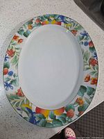 Top view of Lynns oval porcelain platter showing multicolor floral and fruit border and white center