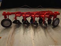 Full view of red diecast five-furrow plow with wheels