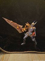 Front view of articulated armored action figure holding large organic-style sword