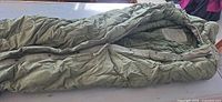 Full view of olive drab mummy sleeping bag, unzipped to show interior