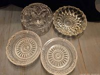 Group shot of four clear cut crystal ashtrays displaying overall condition and patterns