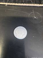 Obverse of token showing UHS monogram and partial inscription