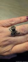 Ring on finger showing front view with black stone and triangular accented design