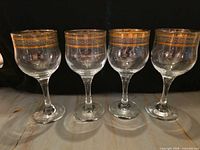 Front view of all four wine glasses with gold decorated rims