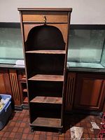 Front view of tall wooden shelf showing four shelves and top drawer