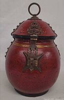 Front view of red lacquered wood jar with brass latch and ring handle