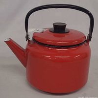 front view of red enamel tea kettle showing spout, body, lid and handle