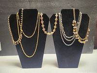 Two display busts showing layered gold and silver tone necklaces