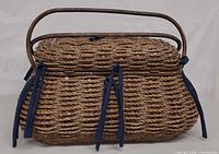 Side view of woven wicker picnic basket with handle and blue ties