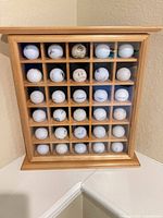 Wooden golf ball display case with 25 balls visible
