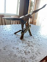 Side view of brass eagle on branch base