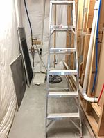 Aluminum step ladder standing upright in storage area
