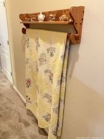 Front view of oak wall-mount quilt rack with shelf showing dowel and top shelf