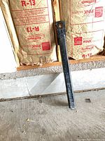 Full view of black steel tow bar leaning against wall