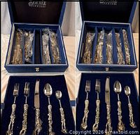 Two presentation boxes opened showing flatware pieces bagged and set in velvet