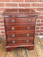 front view of bedside table showing all three drawers and brass pulls