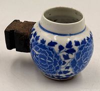 Side view of porcelain feeder showing floral pattern and iron mount