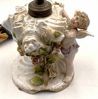 close view of porcelain base showing cherub, shell and roses