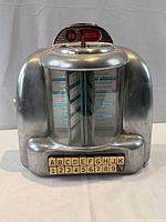 Front view of wall-mount jukebox selector showing housing, glass panels, buttons