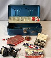 Open tackle box showing insert tray, bobbers, reel and accessory boxes