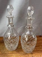 Both matching Waterford crystal decanters with stoppers on wood surface