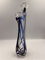 full view of tall clear vase with blue and black swirls