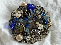 Front view of brooch showing arrangement of beads, rhinestones, faux pearls