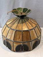 Full view of slag glass hanging lamp shade showing amber vertical panels, green crown, brass hardware