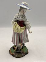 Front view of porcelain figurine showing full attire, posture, and bird on base