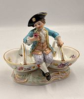 Front angled view of Meissen double salt cellar showing boy figure, baskets, and base details