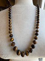 Full view of necklace on display bust showing graduated tiger's eye beads