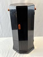 Front view of black octagonal cabinet showing door, bakelite pulls, base wear