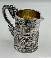 Front angle showing dragon handle, relief decoration, gilt interior, inscription plaque