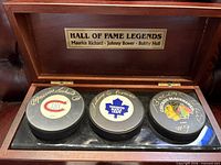 Display case open showing three signed pucks with plaque