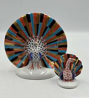 Front view of both peacock figurines showing size difference and fishnet pattern