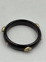 Full view of black bangle showing exterior gold mounts