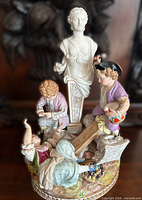 Full view of entire figural group showing children, see-saw and classical bust