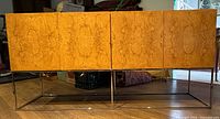 Front view of closed burl walnut credenza on chrome base