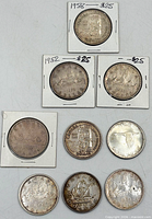 Fronts of nine Canadian silver dollars in holders and loose
