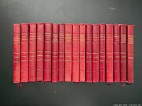 Front view showing all 17 red leather volumes standing side-by-side, gilt titles visible