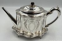 Side view of sterling silver teapot showing body, spout, handle and lid