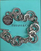 Bracelet displayed on Tiffany blue card, showing chain links, toggle bar, and round tag
