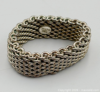 Angled view of woven sterling mesh ring showing hallmark plate